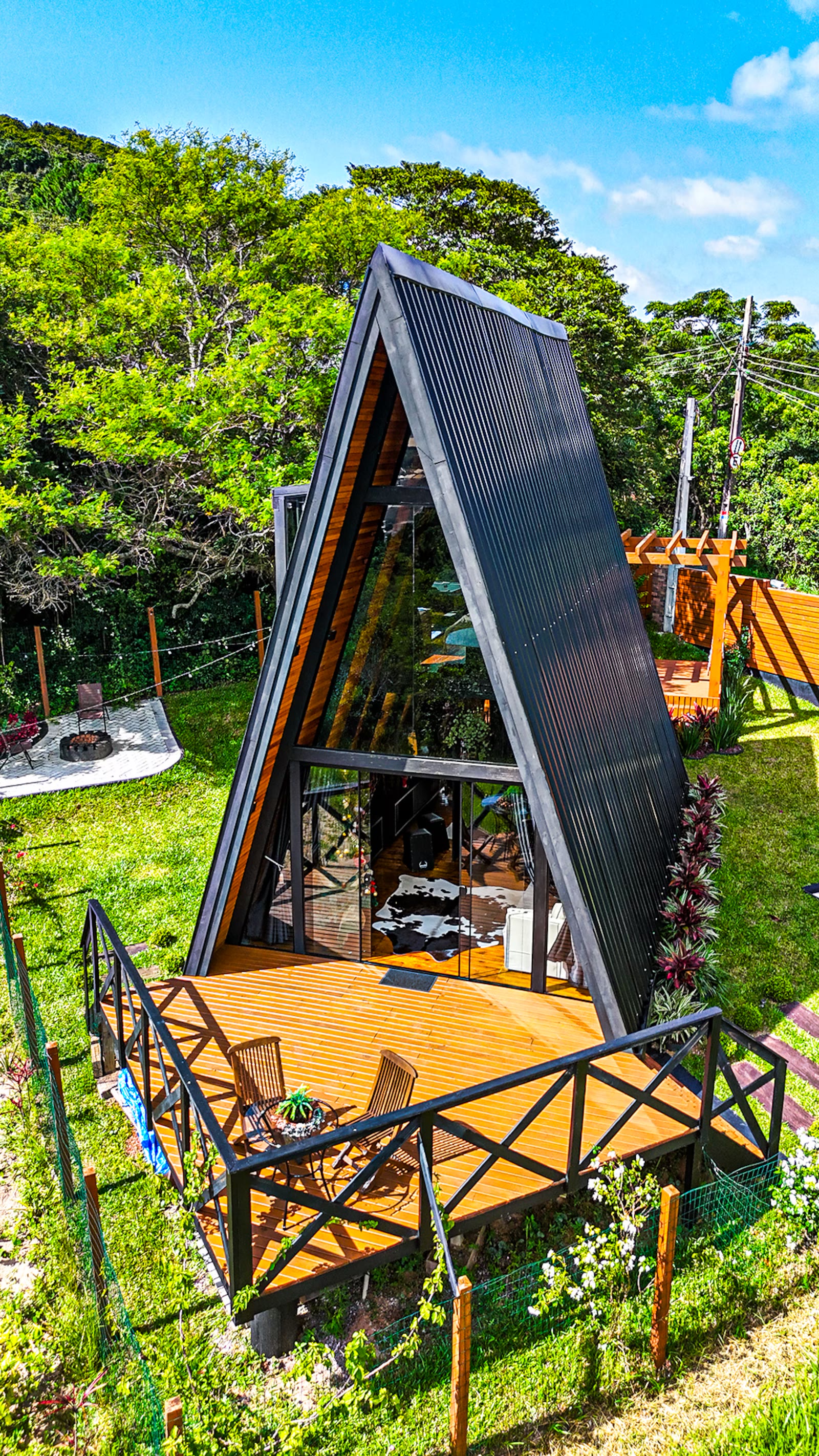 Fachada do chalé A-frame em madeira, cercado de verde na Praia dos Ingleses