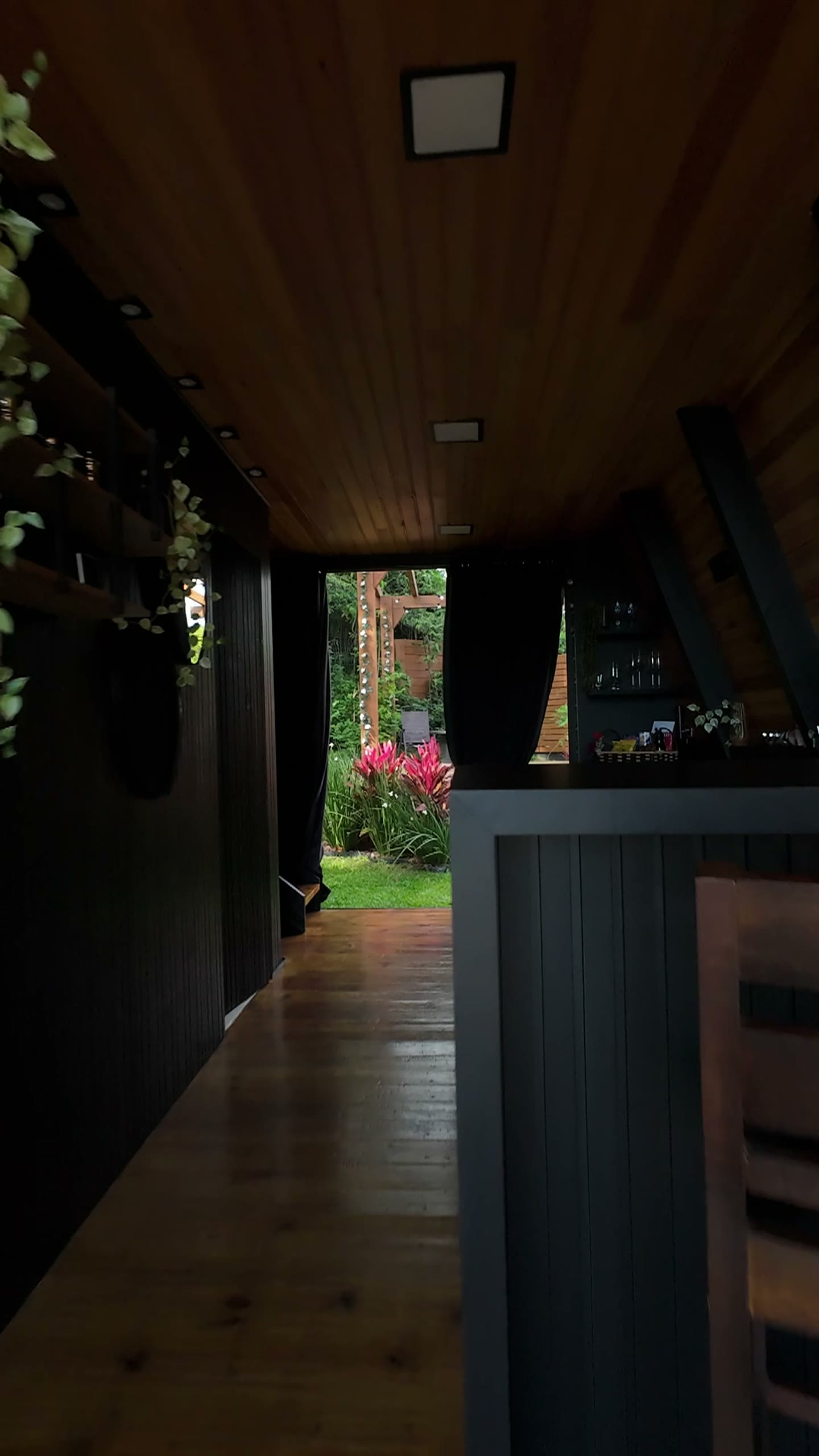 Interior em madeira do chalé aberto para o jardim, visto do balcão
